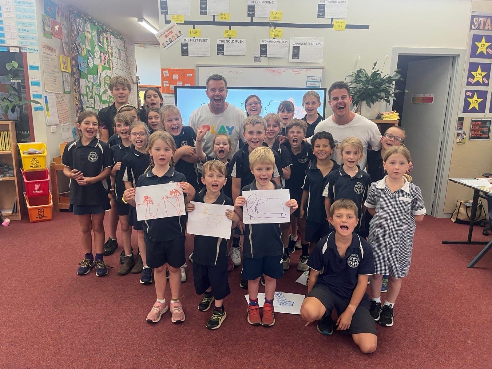 Students excitedly holding up their drawings during a School of Play classroom session