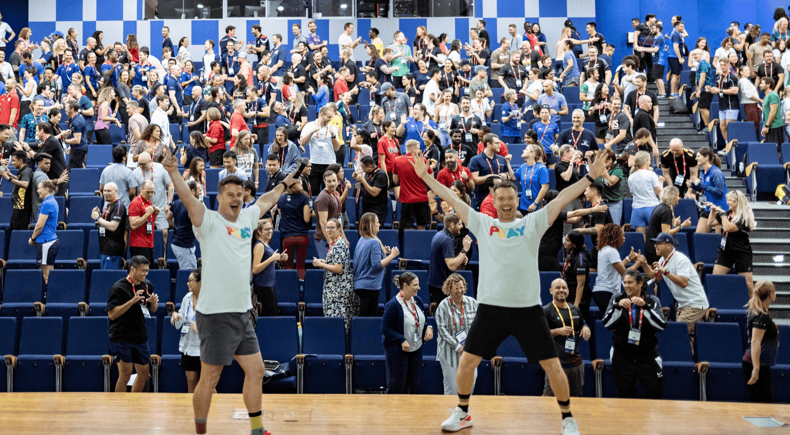 Dale and Paul leading a packed arena through a School of Play session, 2025