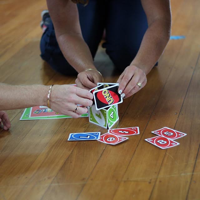 Two people playing a card game together on the floor